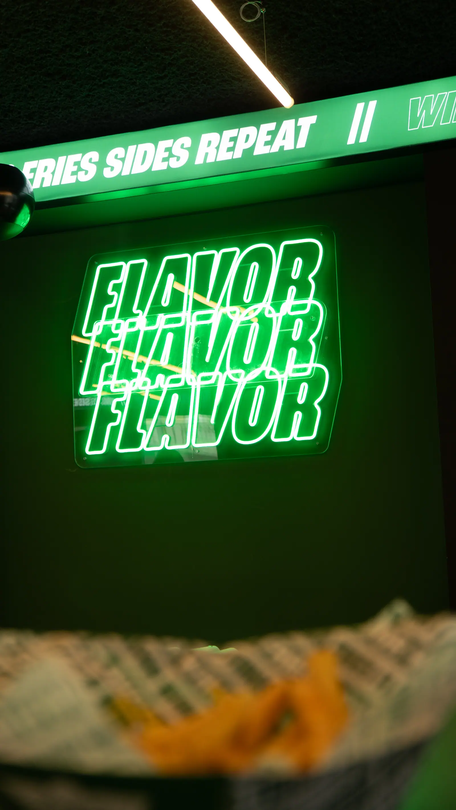 Señalética LED de marca WingStop en neón verde contra fondo oscuro del evento