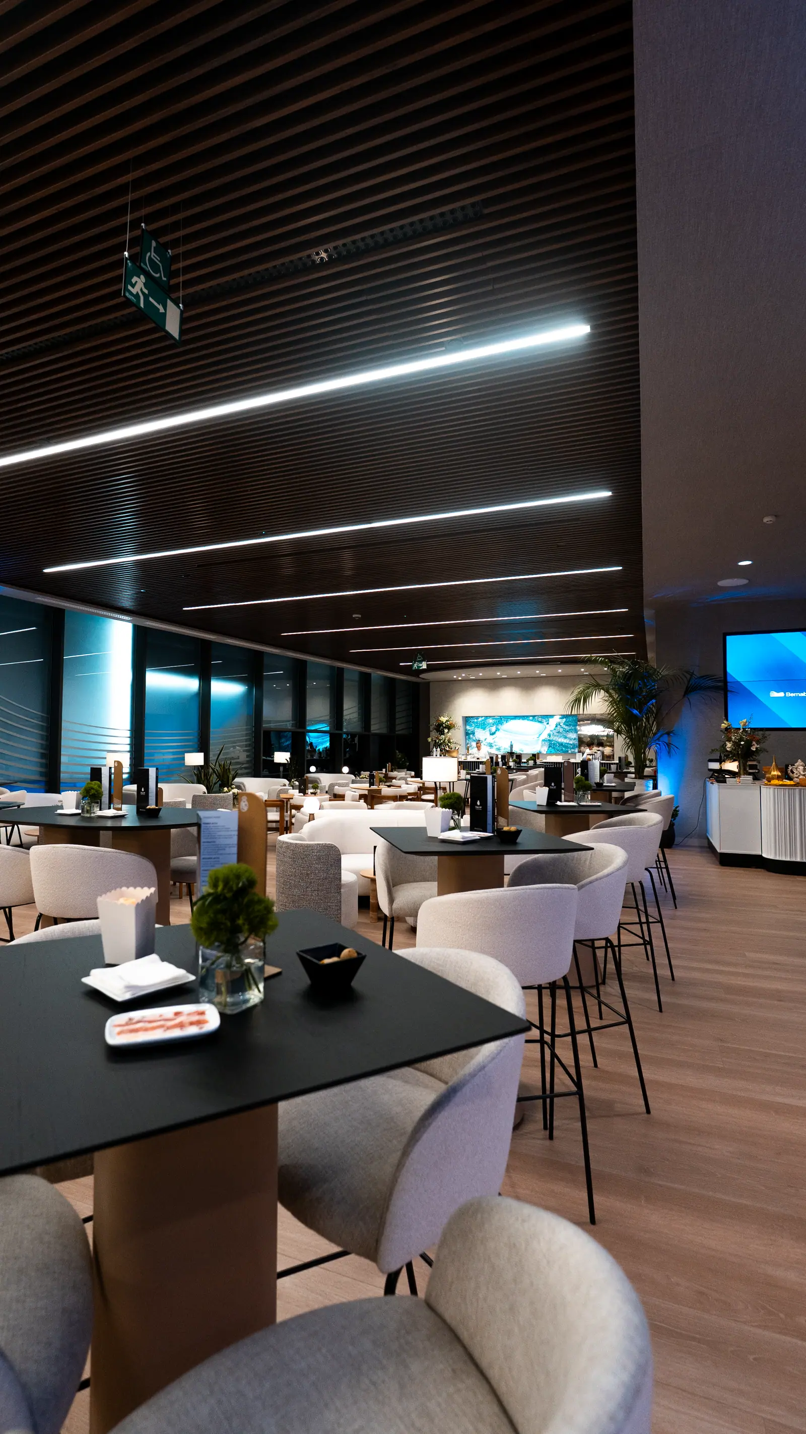 Salón de eventos elegante con iluminación azul saturada y piso de madera para evento corporativo premium.